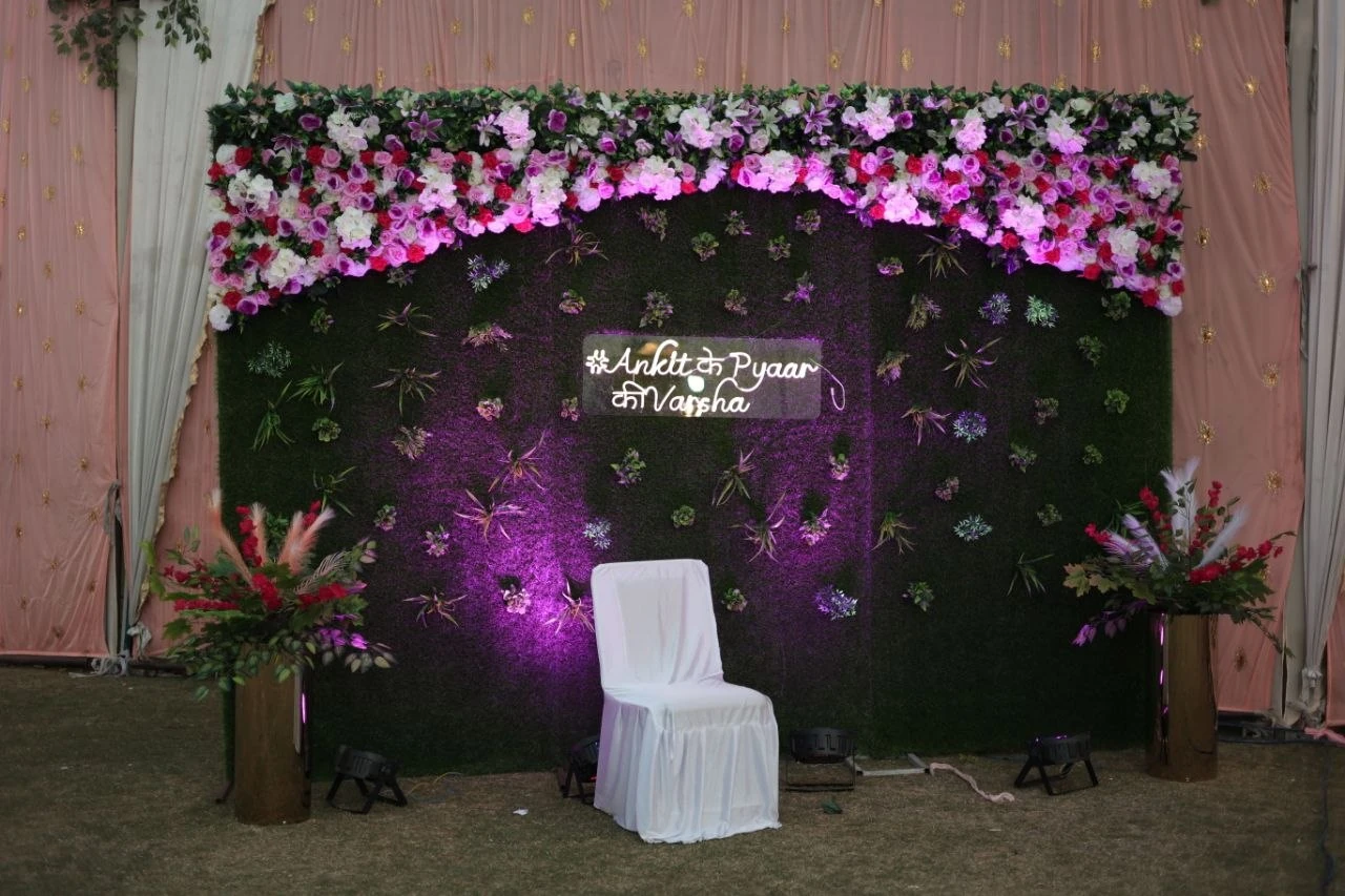 Pink and white floral backdrop with greenery and purple accent lighting