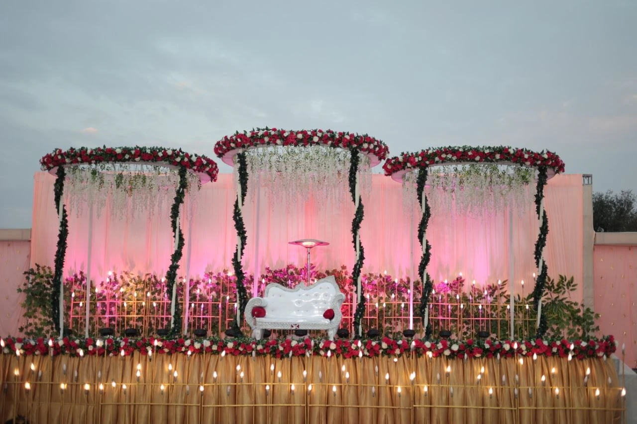 Pink floral wedding stage with hanging flowers, white drapes and a white sofa